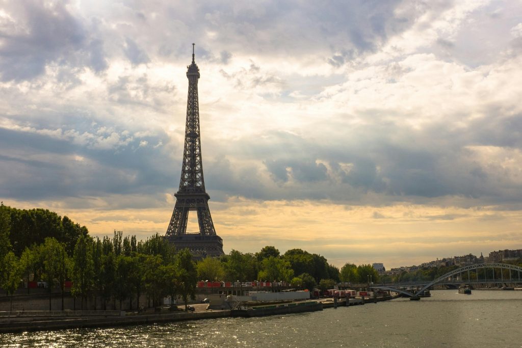 Stunning view of the Eiffel Tower at sunset with the River Seine and lush green trees.