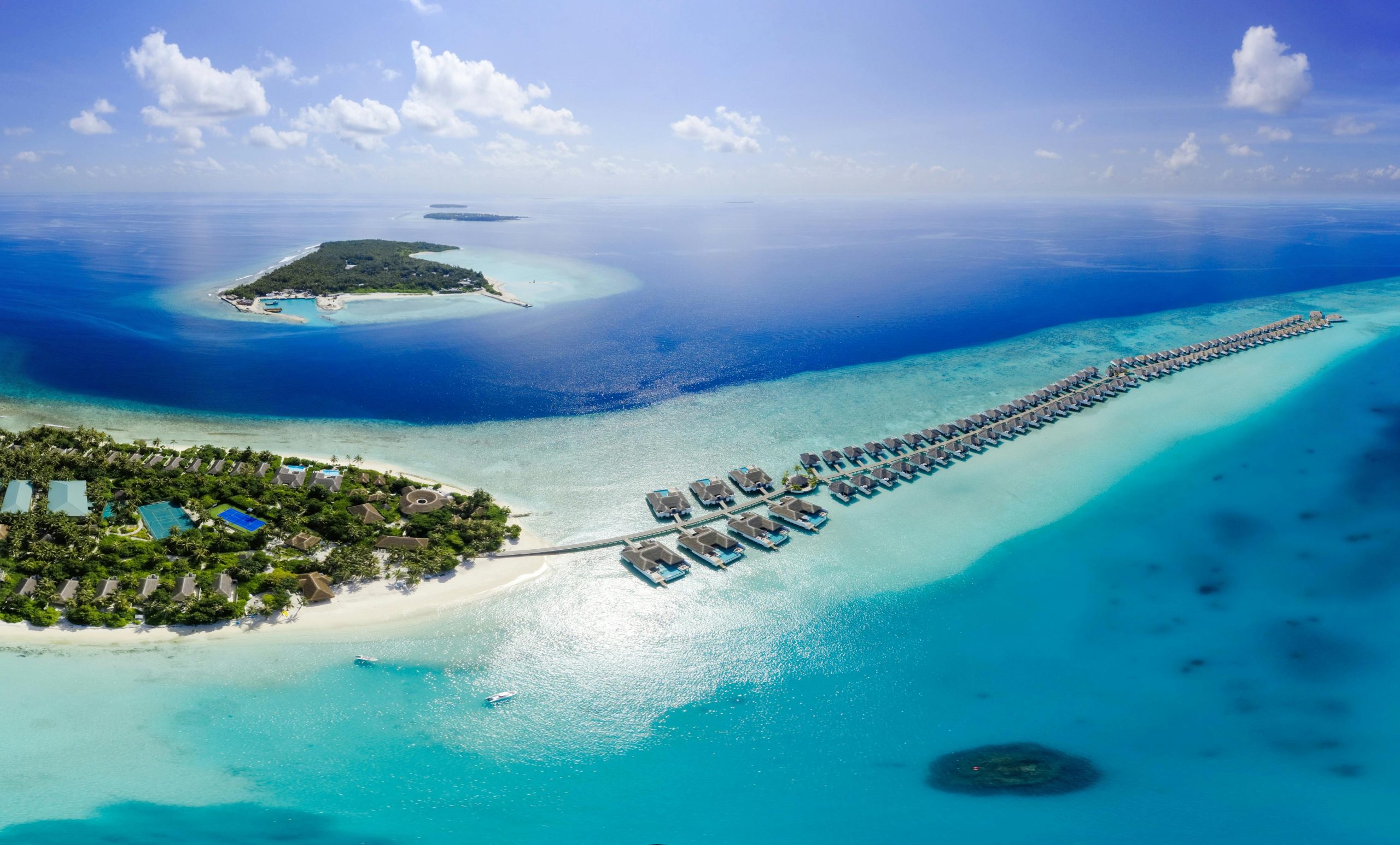 Breathtaking aerial view of Maldives island resorts with azure waters and lush greenery.