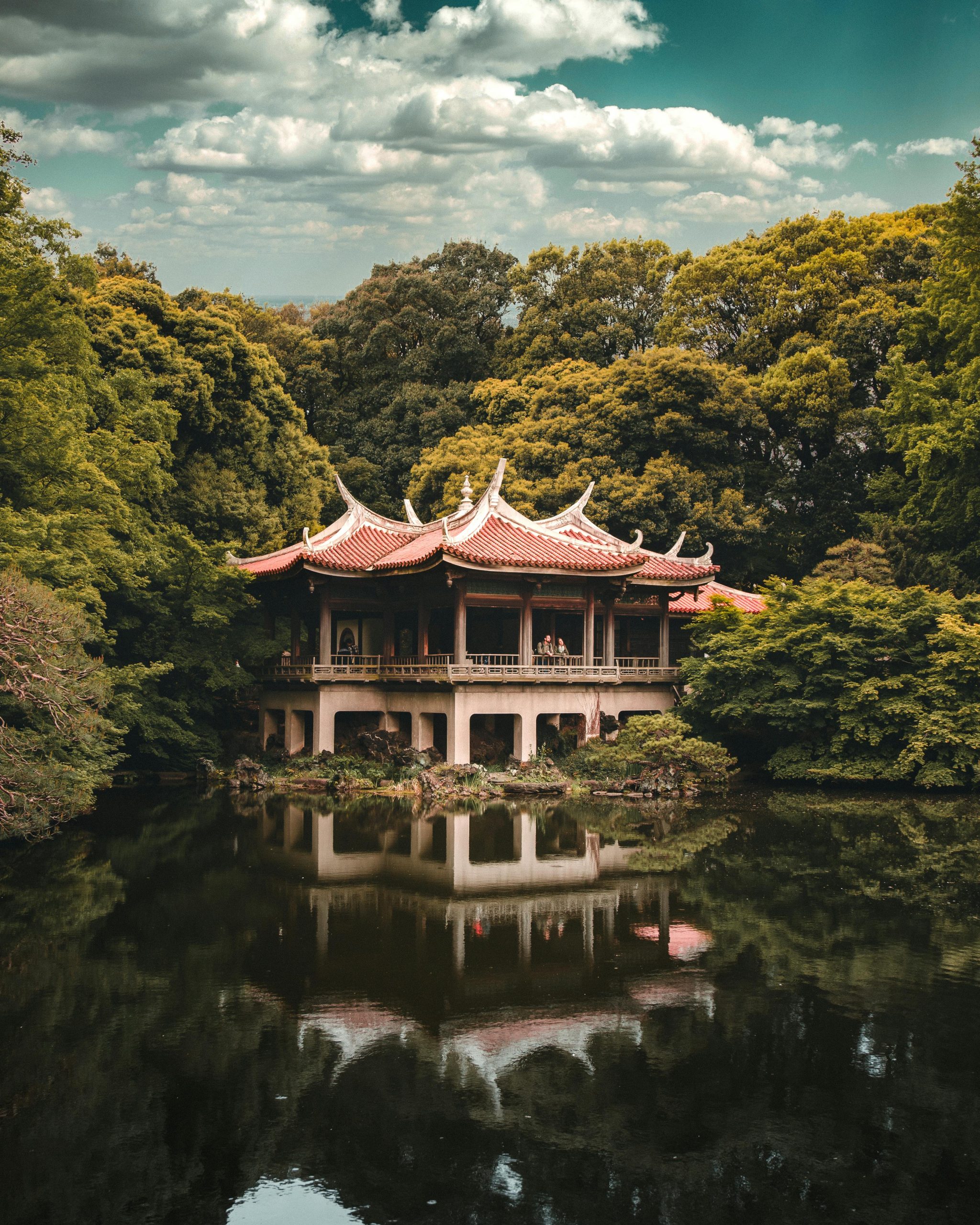 A beautiful traditional Japanese pagoda surrounded by lush greenery and reflected in a peaceful lake.